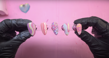 Handmade press-on nails with pastel swirls and floral designs on a pink background