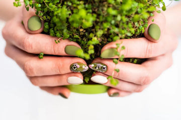 Hands with green and floral handmade press-on nails holding a potted plant