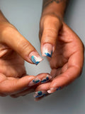 Hand with nude base press-on nails featuring 3D blue butterfly and chrome accents.