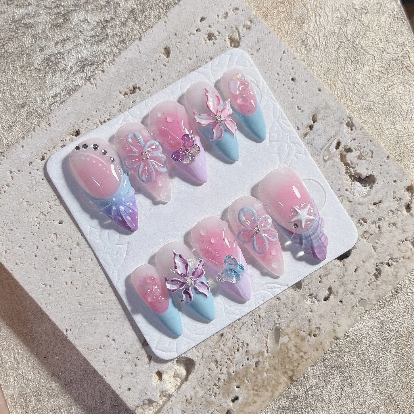 Handmade 3D press-on nails with butterfly, floral, and pastel ribbon bow designs.