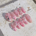 Handmade pink press-on nails with 3D butterfly, seashell, floral, and pearl gem accents