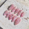 Handmade pink press-on nails with 3D butterfly, seashell, pearl, and floral gem designs