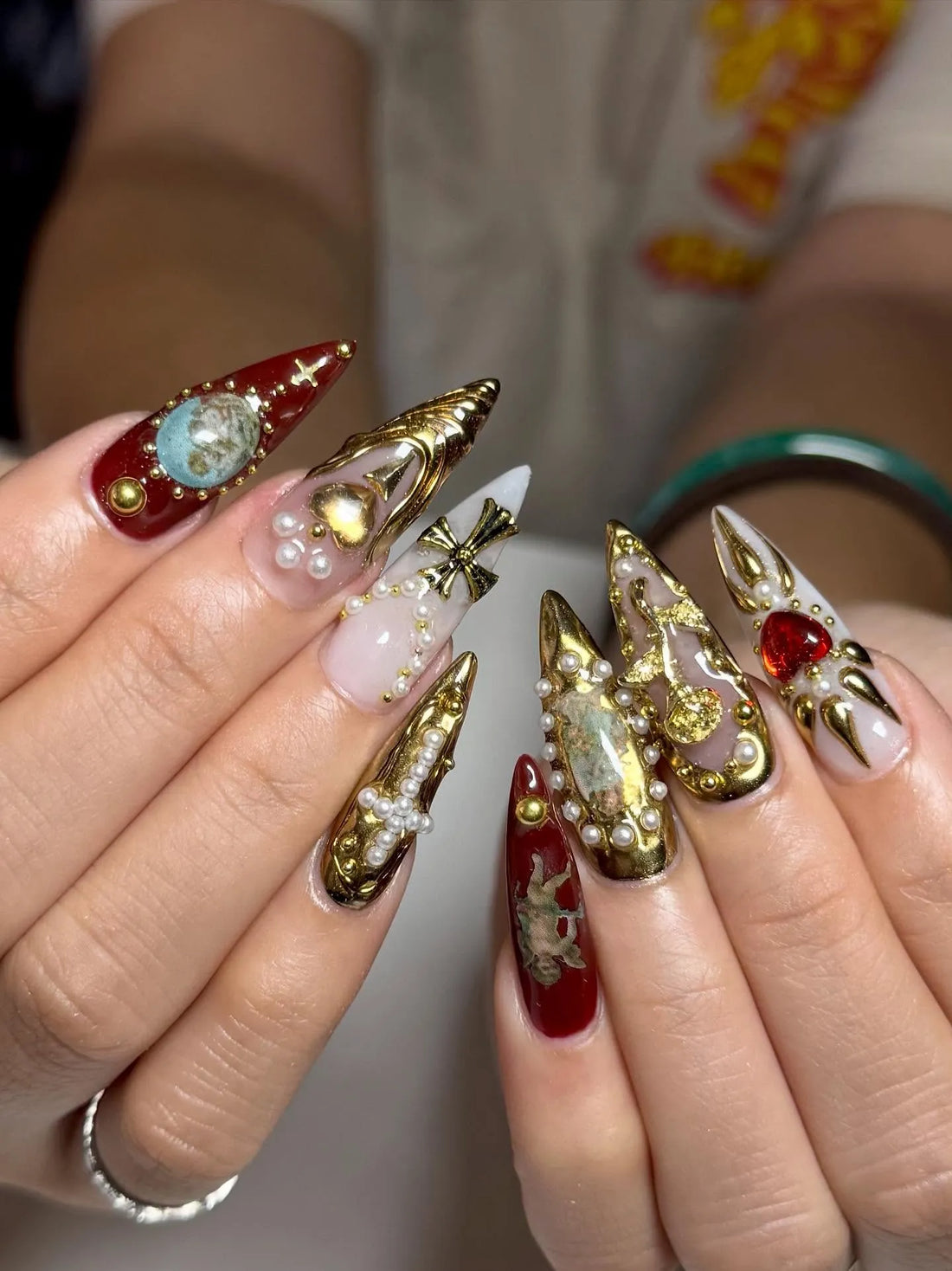 Handmade press-on nails with baroque designs, gold crosses, pearls, red and gold accents.