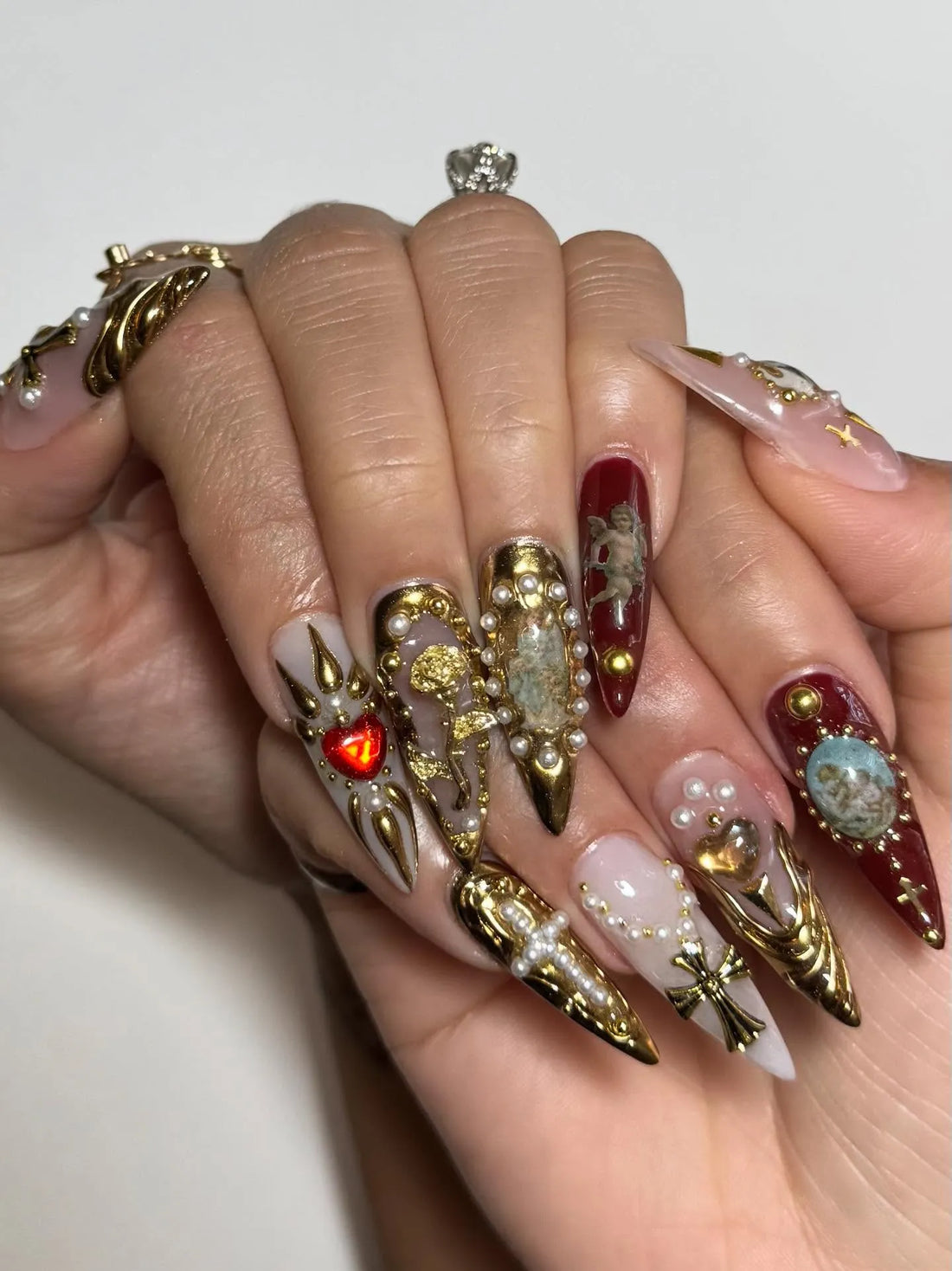 Handmade press-on nails with baroque designs, gold crosses, pearls, red and gold accents.