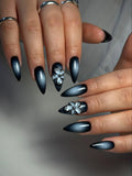 Hand with long stiletto black ombre press-on nails and 3D floral butterfly accents