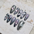 Handmade black and chrome press-on nails with silver star, butterfly, and heart accents
