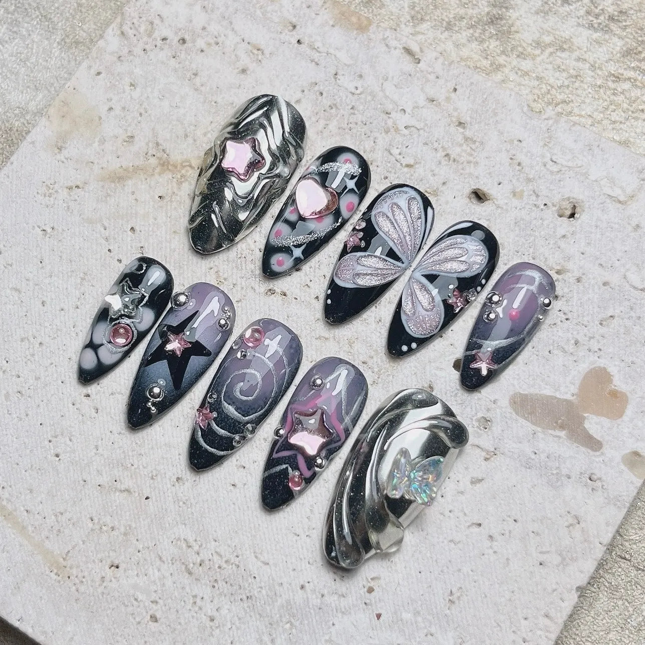Handmade black and chrome press-on nails with silver star, butterfly, and heart accents