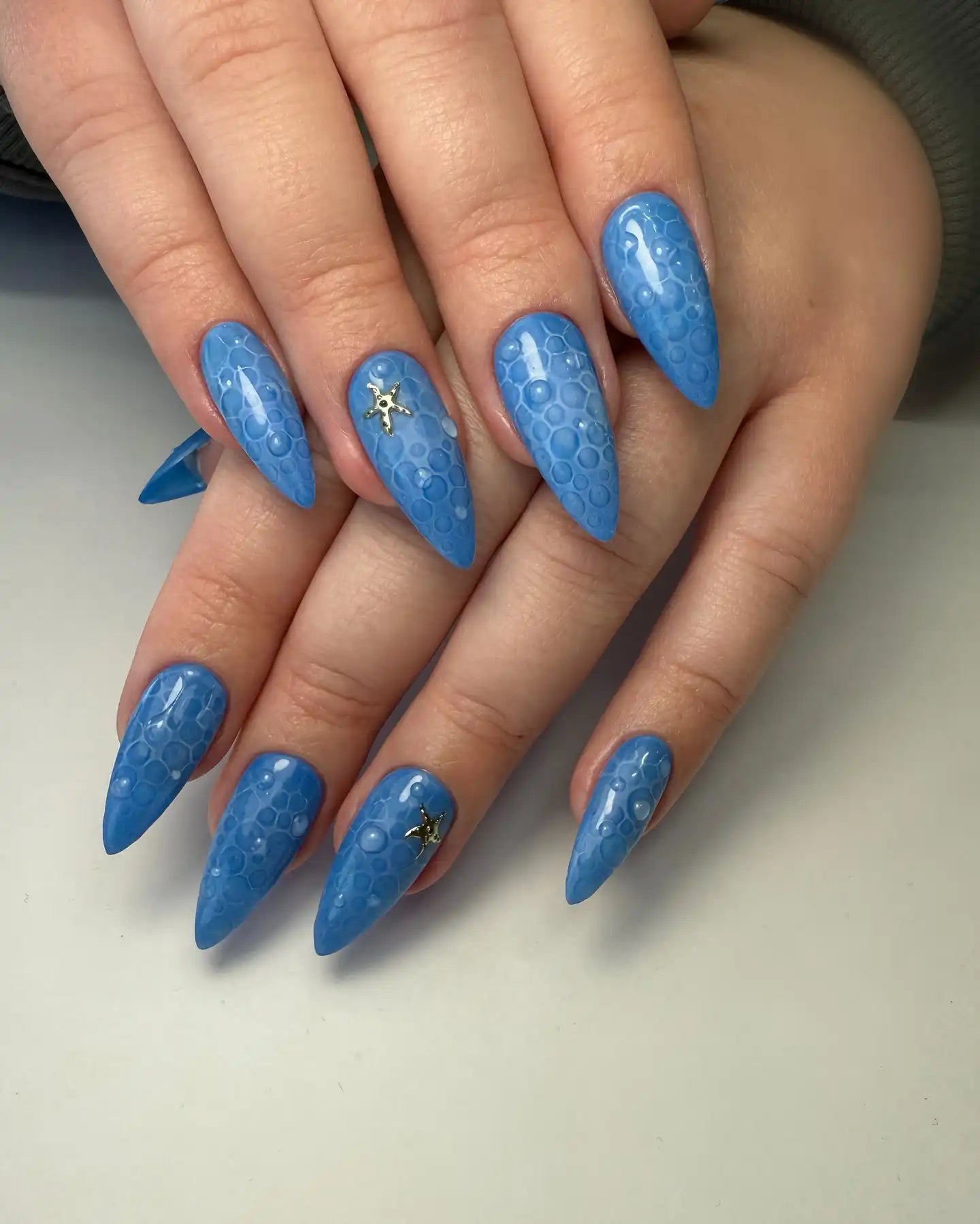 Handmade blue press-on nails with bubble texture and 3D starfish ocean sea accents.