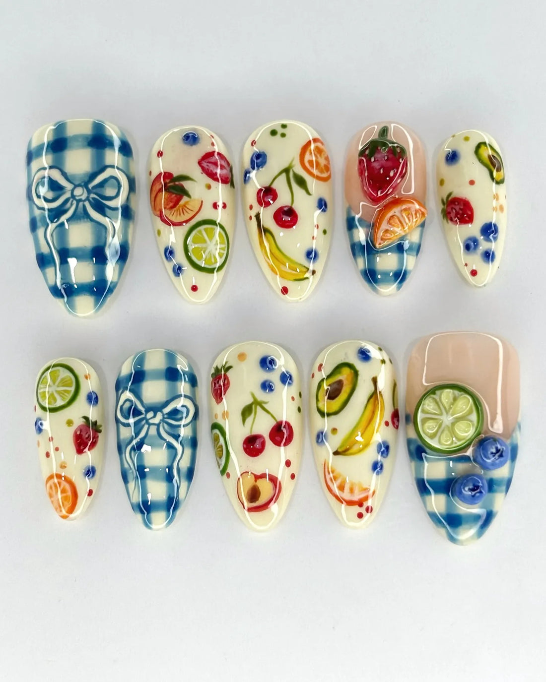 Handmade press-on nails with blue gingham, fruit designs, and 3D bow accents.