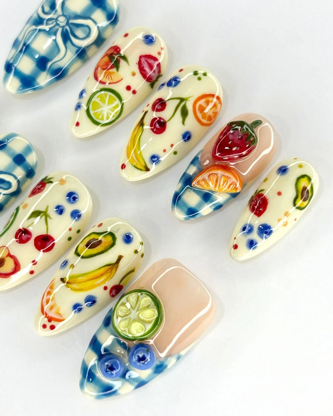 Handmade press-on nails with blue gingham, fruit designs, and 3D bow accents.
