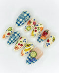 Handmade press-on nails with blue gingham and colorful 3D fruit picnic designs