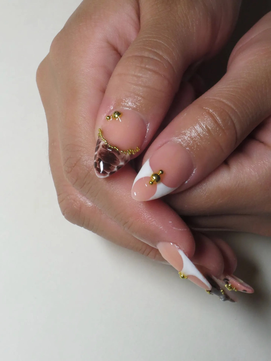 Handmade press-on nails with brown leopard and zebra print French tips, gold bead accents.