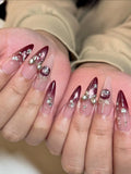 Hand with handmade burgundy stiletto press-on nails, silver bow, metallic accents, gems
