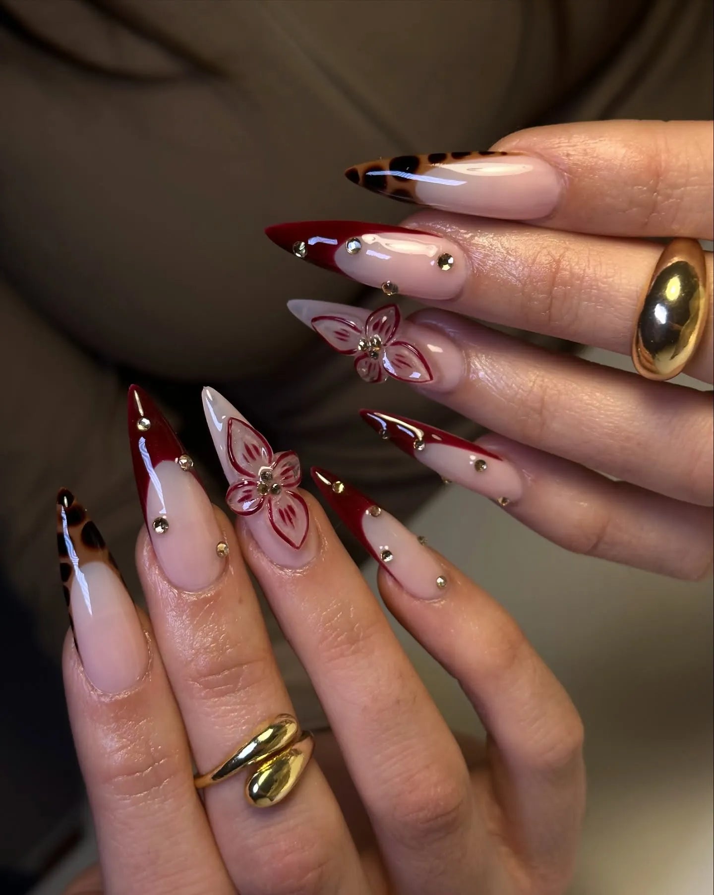 Handmade stiletto press-on nails with burgundy tips, leopard print, gold studs, and 3D floral accents