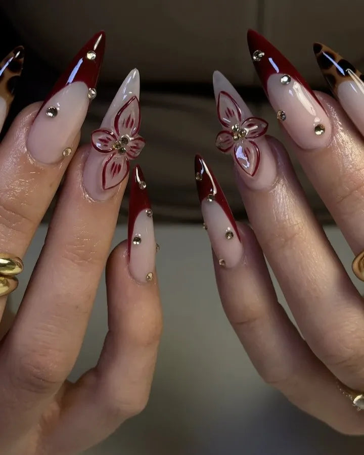 Handmade burgundy red French tip press-on nails with 3D floral and leopard print accents.
