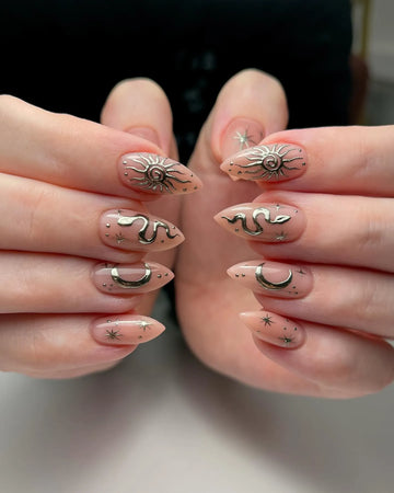 Handmade nude press-on nails with gold chrome sun, moon, snake, and star celestial art.