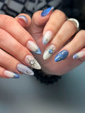 Handmade press-on nails with celestial sun, moon, and star designs in blue and white tones.
