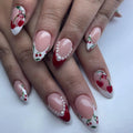 Handmade press-on nails with cherry heart art, red French tips, and pearl accents.