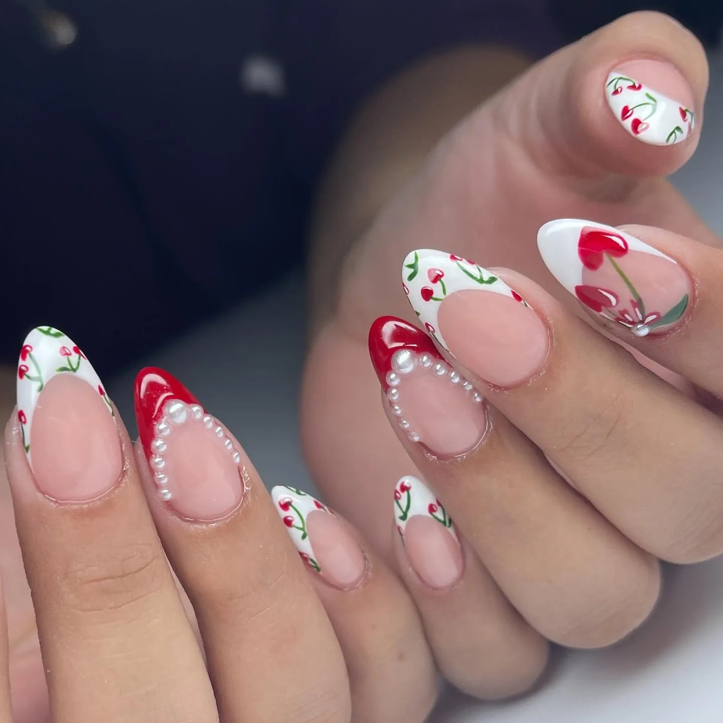 Handmade press-on nails with cherry heart art, red French tips, and pearl accents