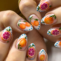 Handmade press-on nails with orange and grapefruit fruit art and blue polka dots
