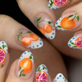 Handmade press-on nails with citrus fruit and grapefruit nail art, blue dot accents