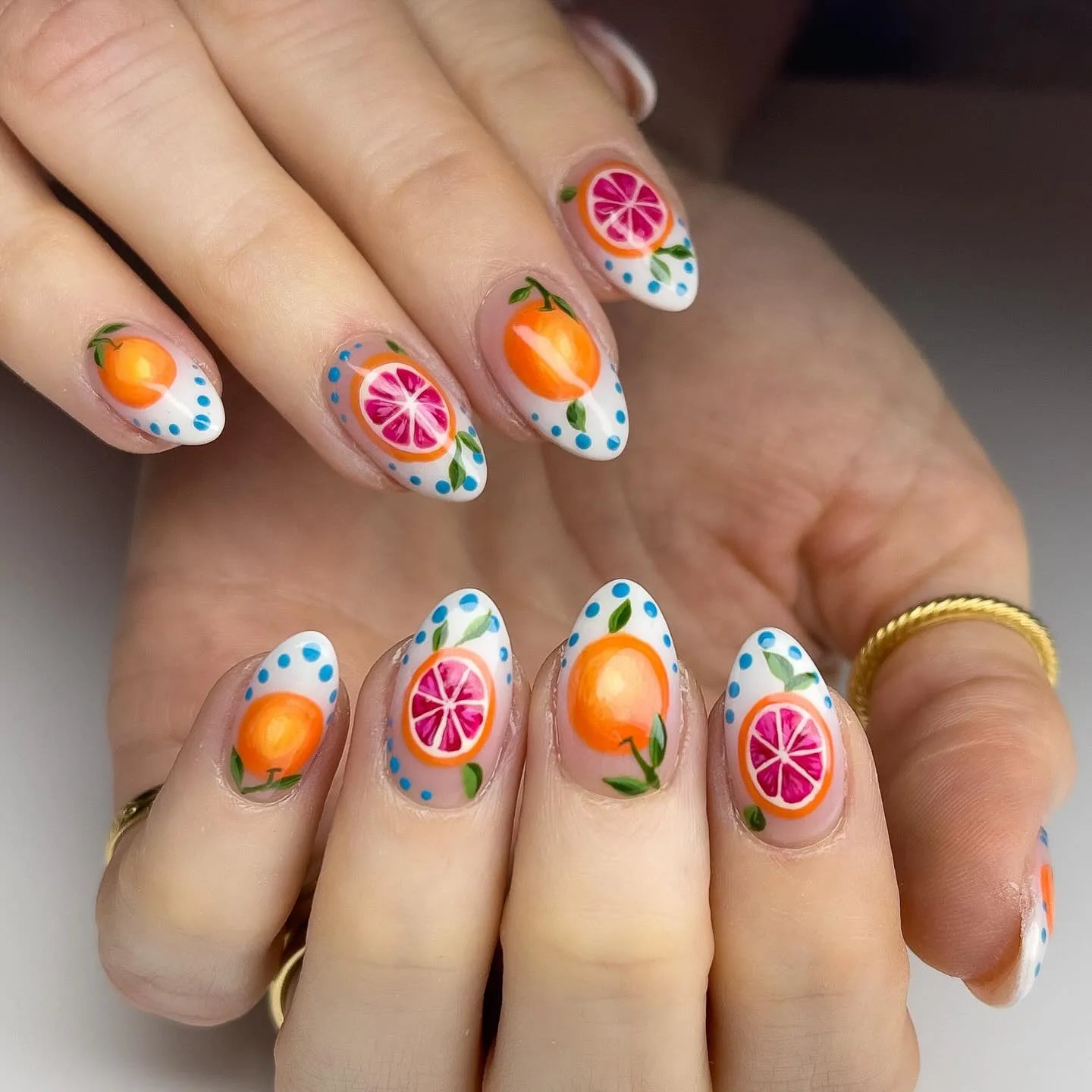 Handmade press-on nails with vibrant orange and grapefruit fruit art and blue dotted accents.