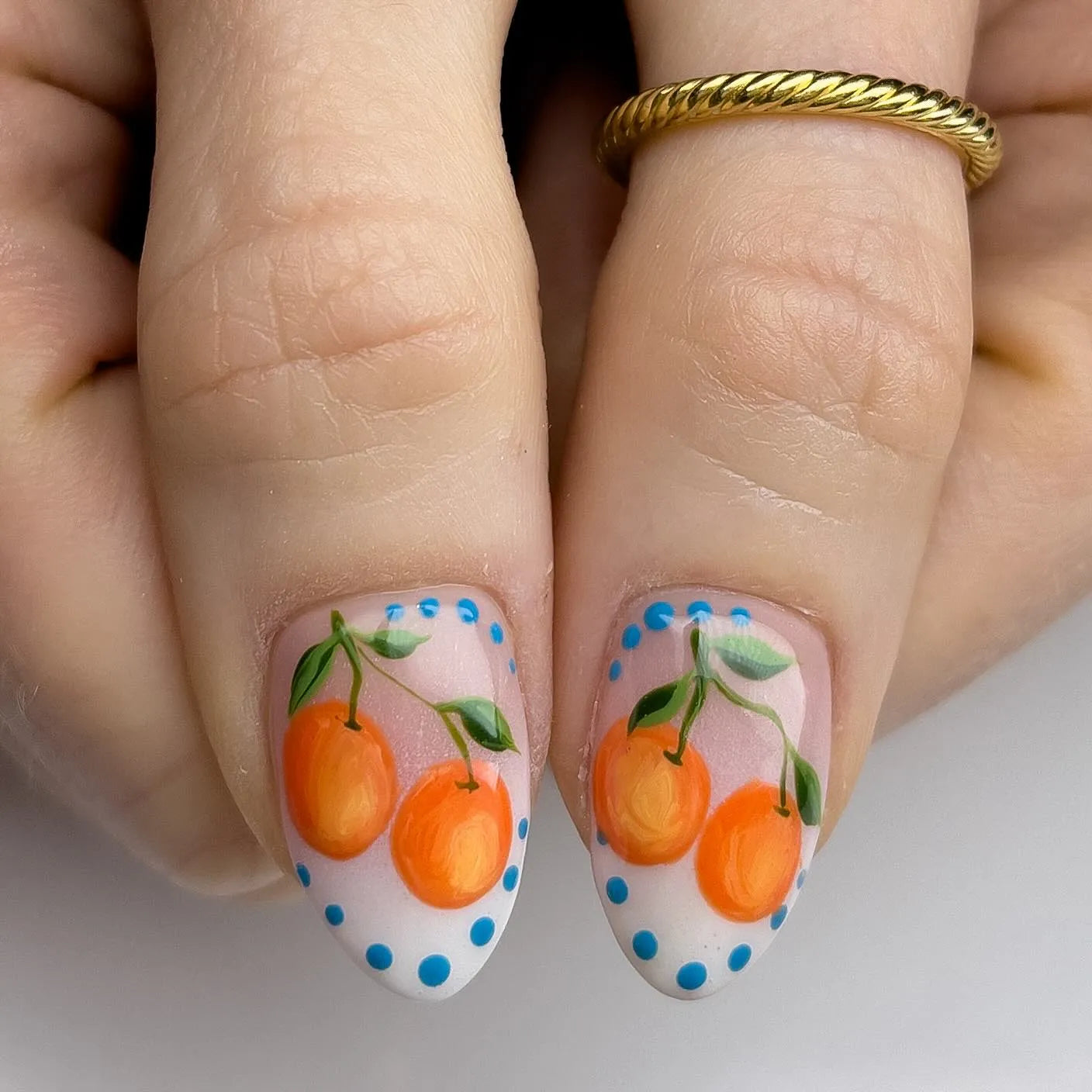 Handmade press-on nails with orange citrus fruit art and blue dotted accents