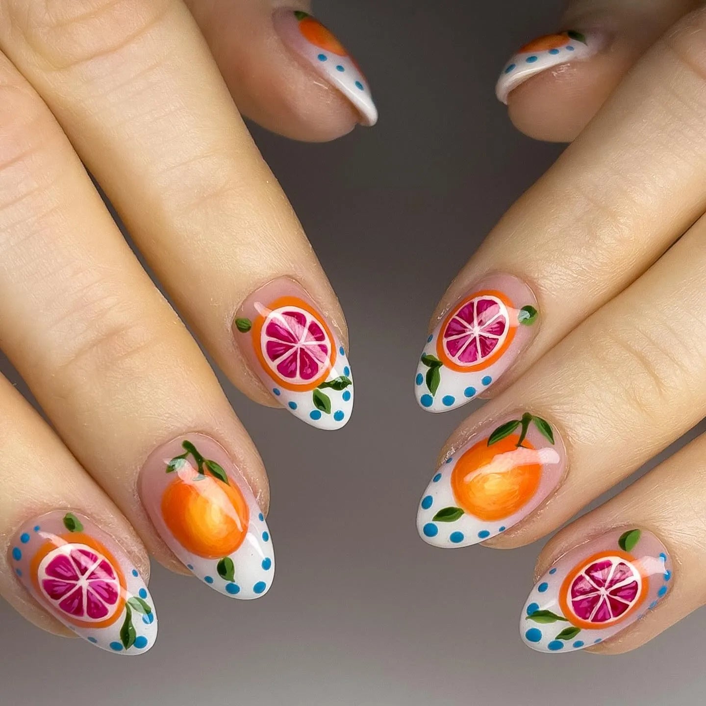 Handmade press-on nails with orange, grapefruit, and leaf fruit art on almond shape nails.