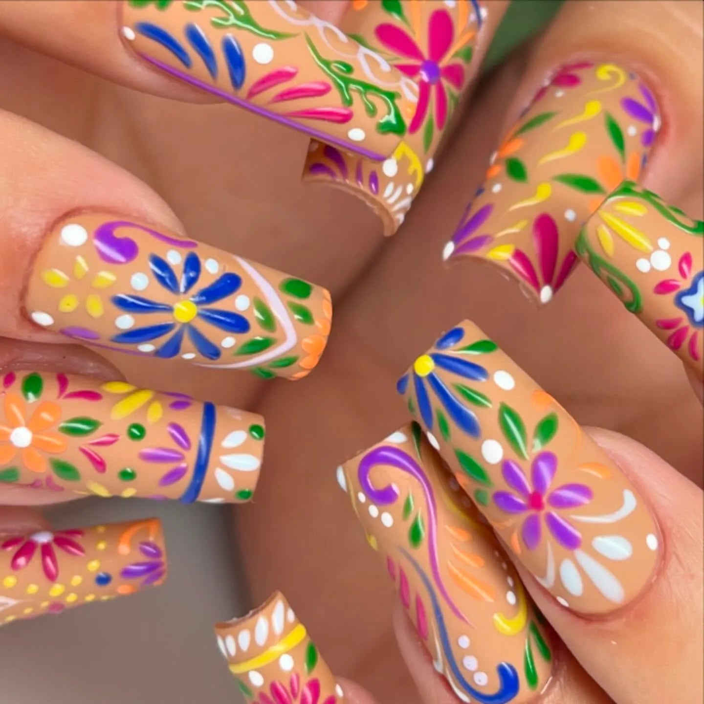 Handmade press-on nails with vibrant folk art floral summer designs in bright colors.