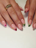Hand with handmade press-on nails featuring colorful reptile print and French tips