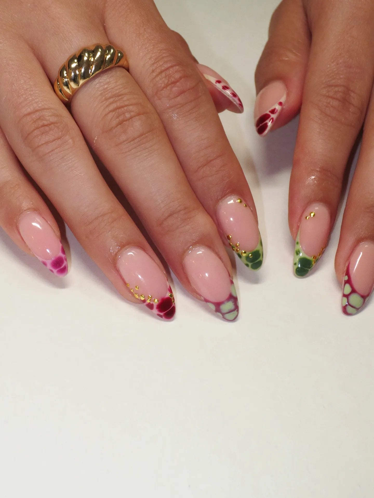 Hand with handmade press-on nails featuring colorful reptile print and French tips