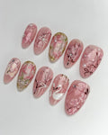 Handmade pink press-on nails with swan, cherry blossom, ribbon, pearl, and gold accents