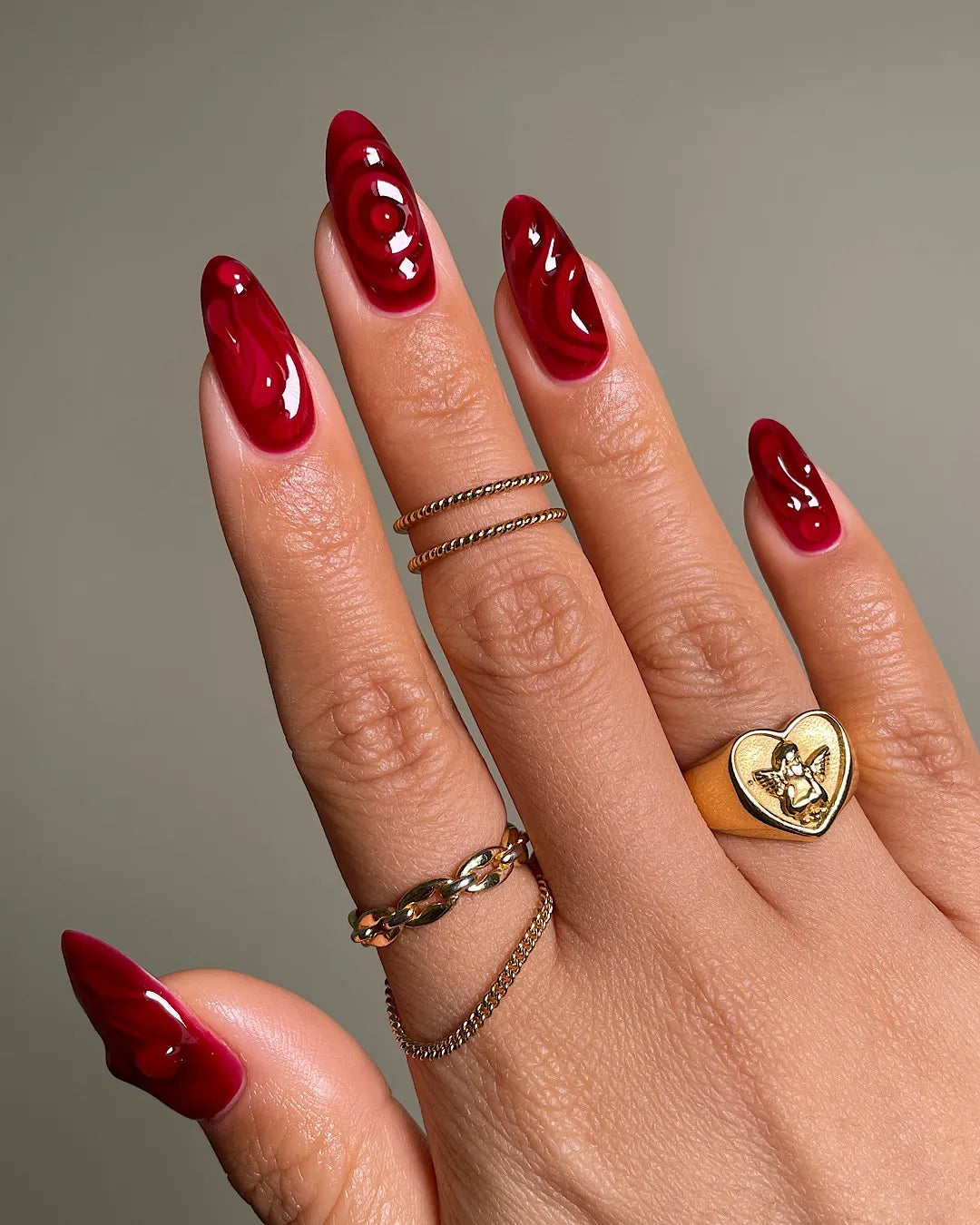 Hand with handmade crimson red swirl 3D jelly aura gemstone press-on nails