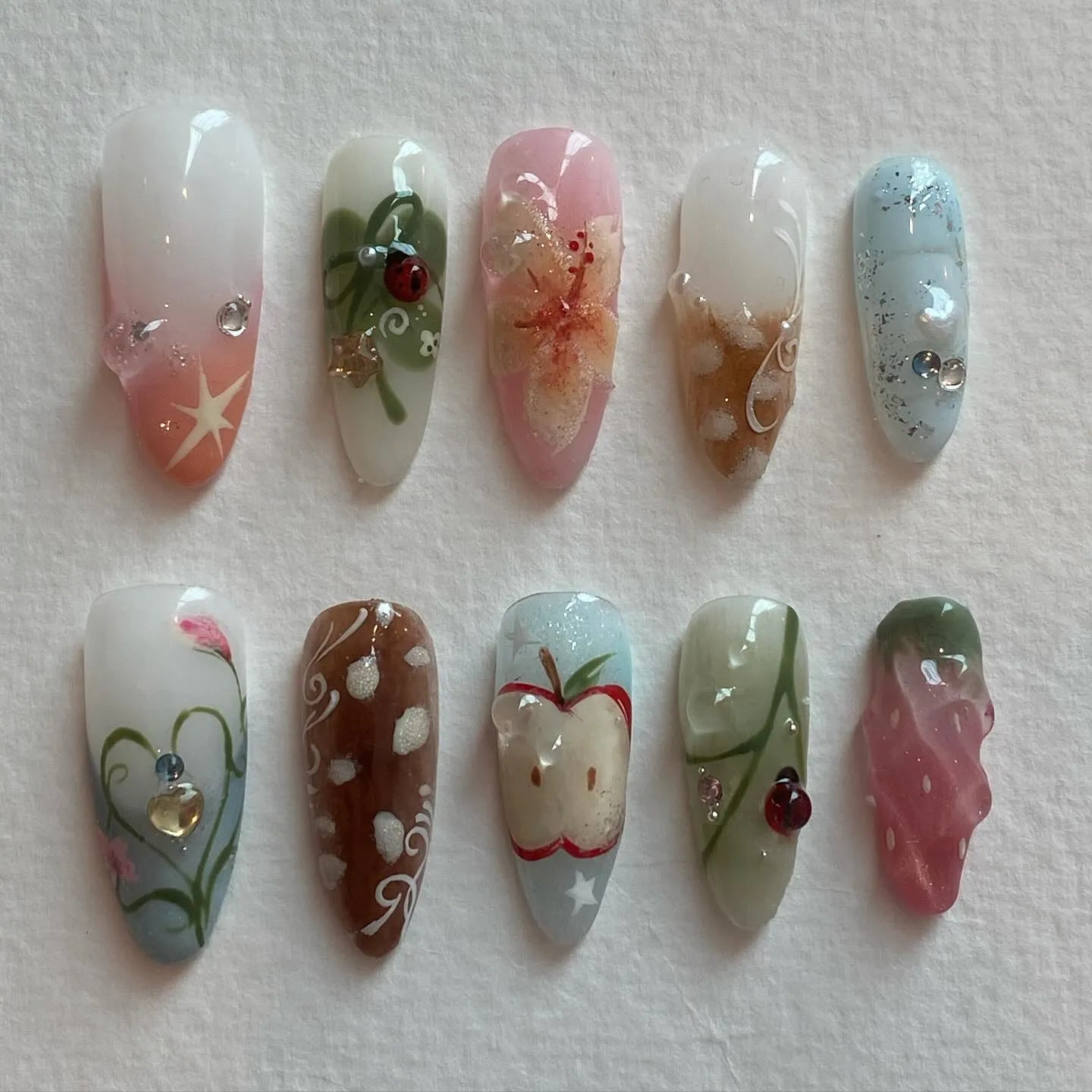 Handmade press-on nails with summer fruit, ladybug, apple, floral, and whimsical picnic designs.