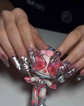 Hand with stiletto-shaped metallic chrome pink and silver 3D floral press-on nails