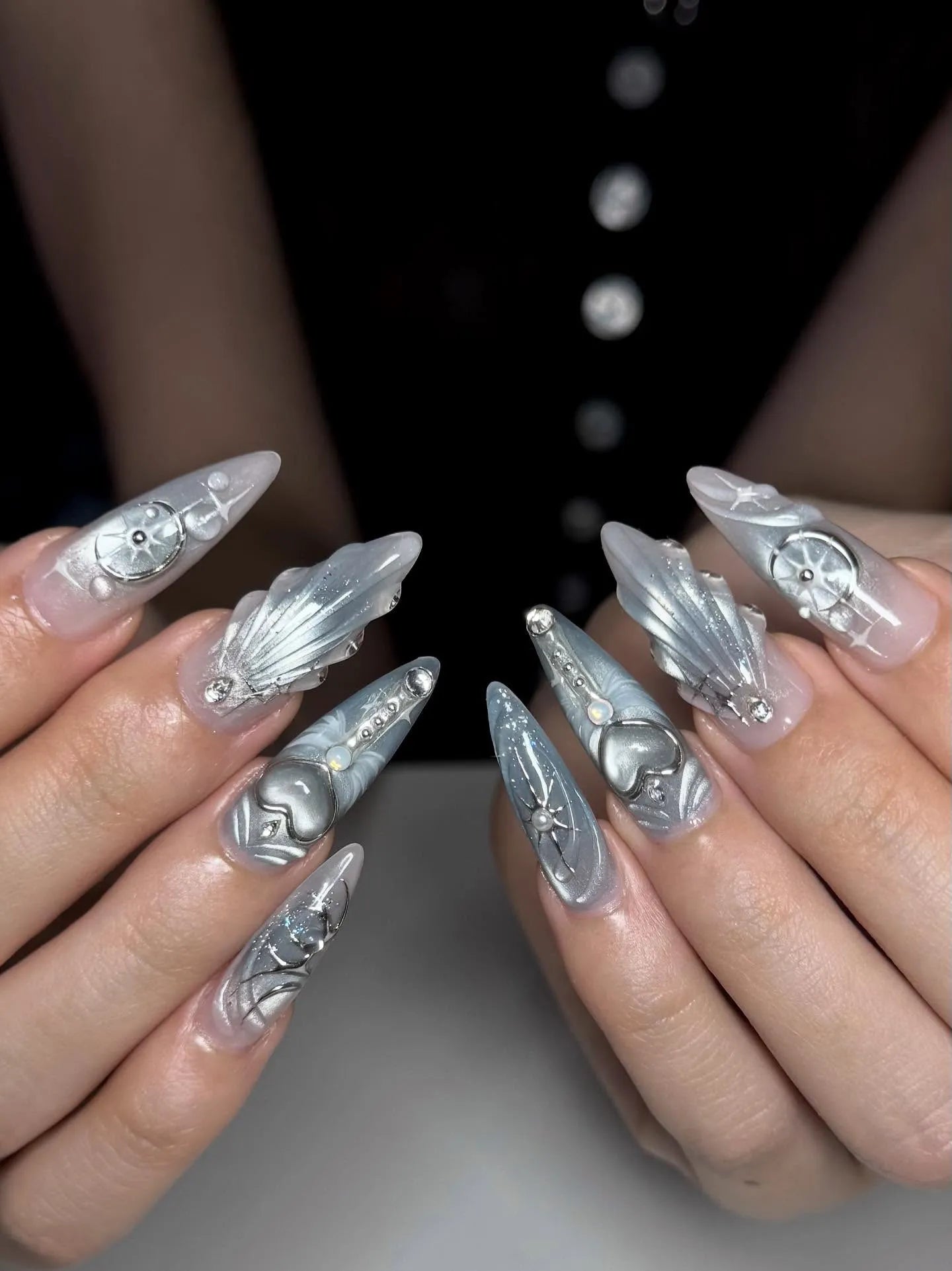 Handmade silver metallic press-on nails with celestial and heart designs, long stiletto shape.