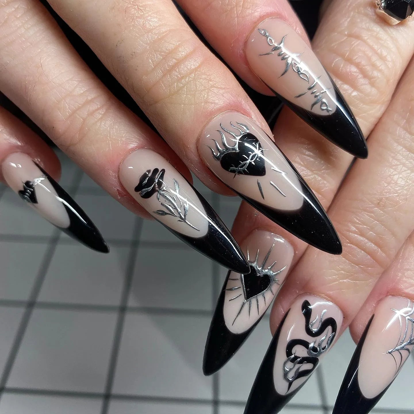 Handmade long stiletto press-on nails with black French tips, gothic heart, rose, and spider designs.