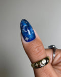 Handmade blue press-on nail with galaxy night sky, moon, and sparkling star design