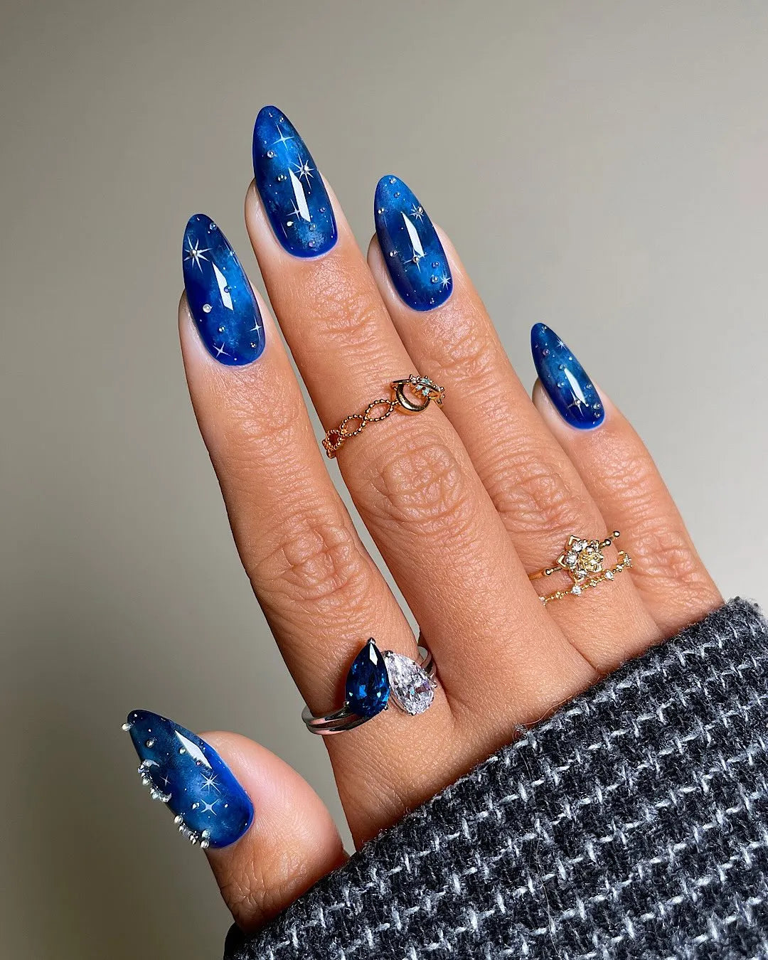 Hand with handmade deep blue galaxy night sky press-on nails featuring sparkling star accents.
