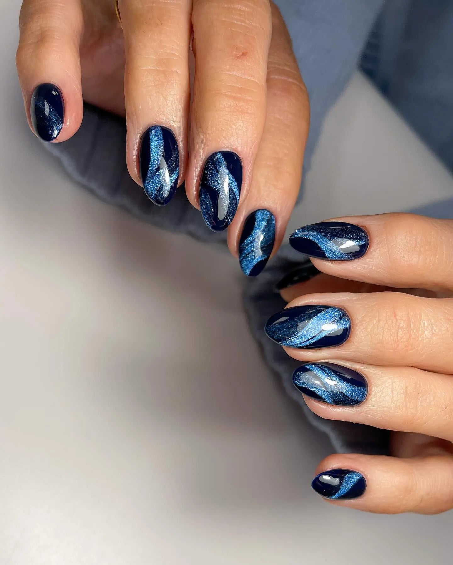 Hand with almond-shaped deep navy blue galaxy cat eye velvet shimmer press-on nails