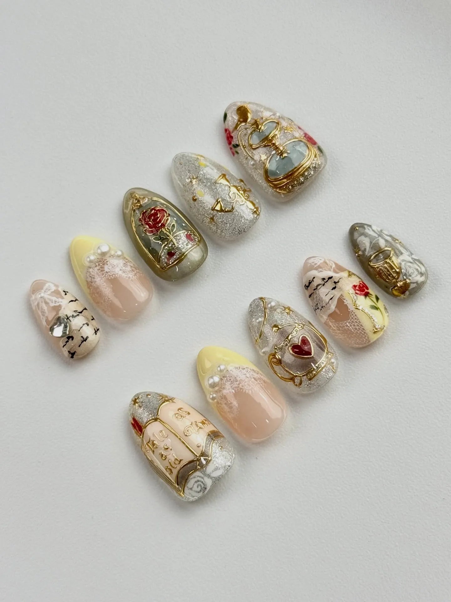 Handmade fairytale press-on nails with gold accents, roses, pearls, and storybook designs