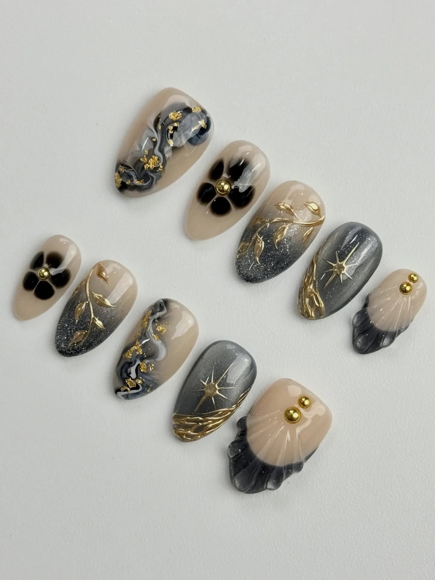 Handmade grey and gold celestial starburst marble press-on nails with floral and metallic details.