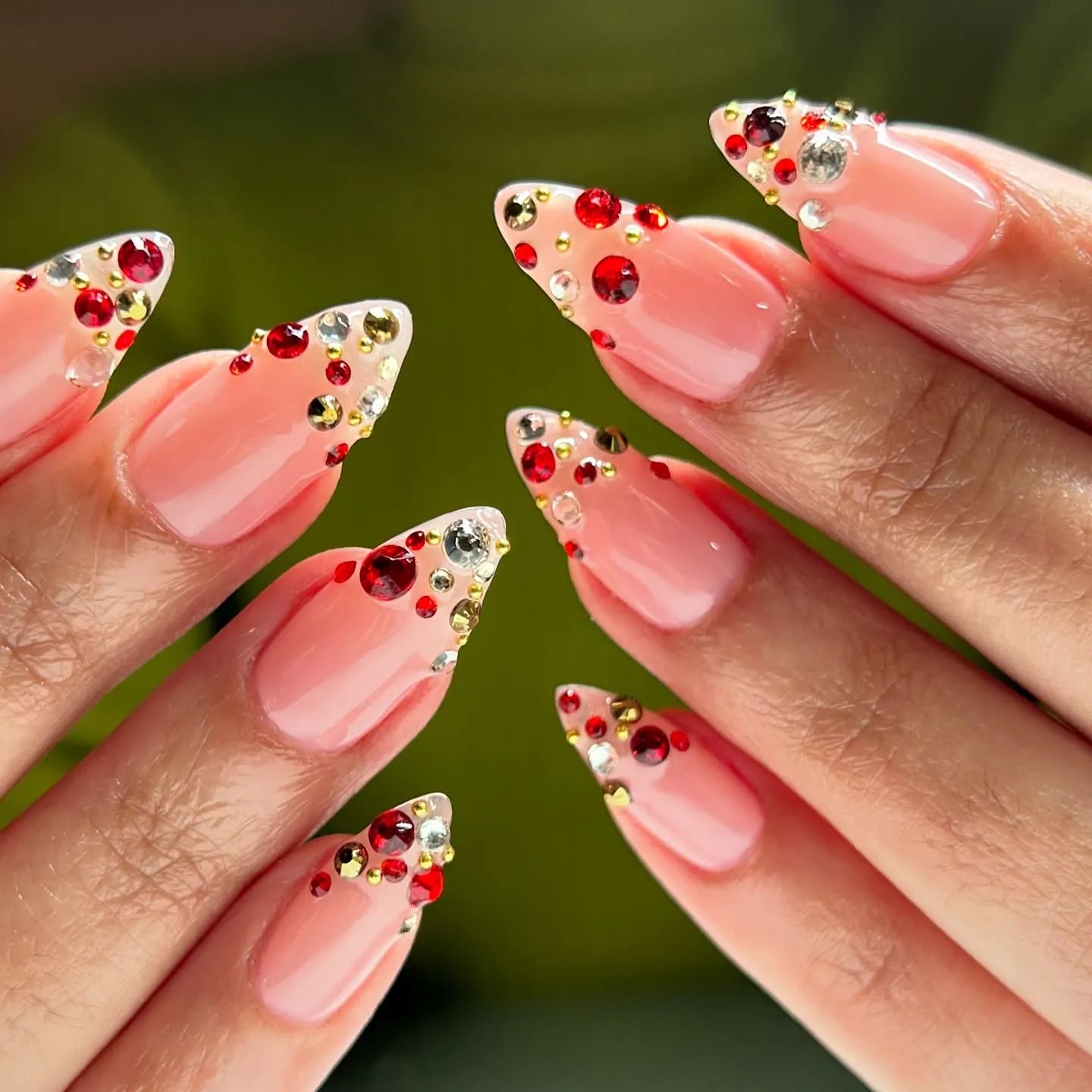 Handmade almond press-on nails with red, gold, and clear crystal accents