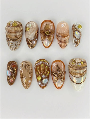 Handmade beach-themed press-on nails with gold starfish, seashell, and ocean-inspired designs.