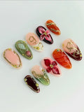 Handmade press-on nails with 3D red floral designs, golden filigree, and gemstone accents.
