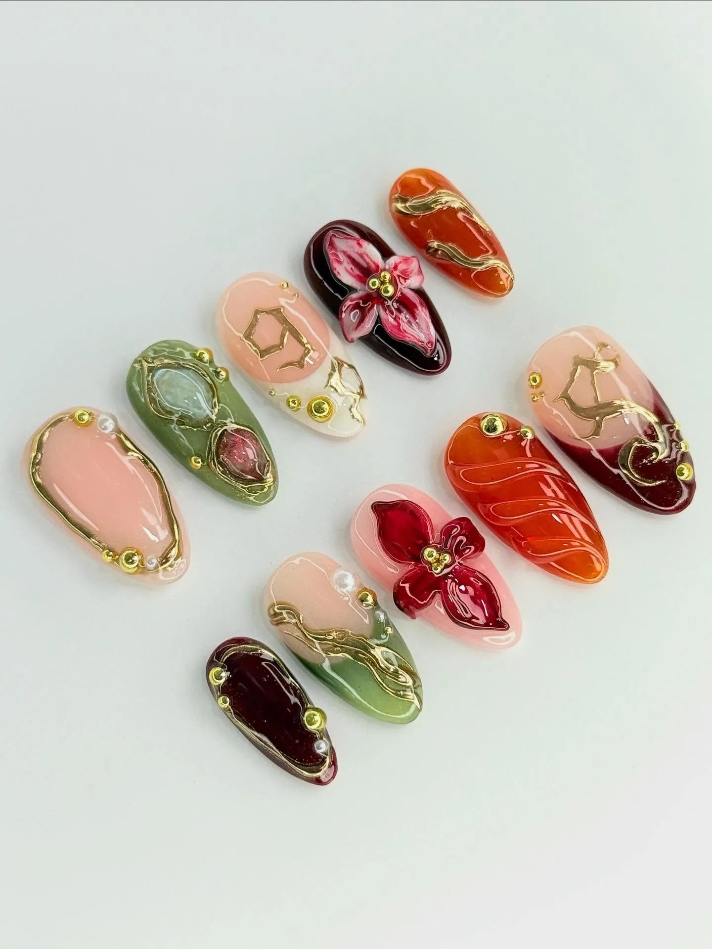 Handmade press-on nails with 3D red floral designs, golden filigree, and gemstone accents.