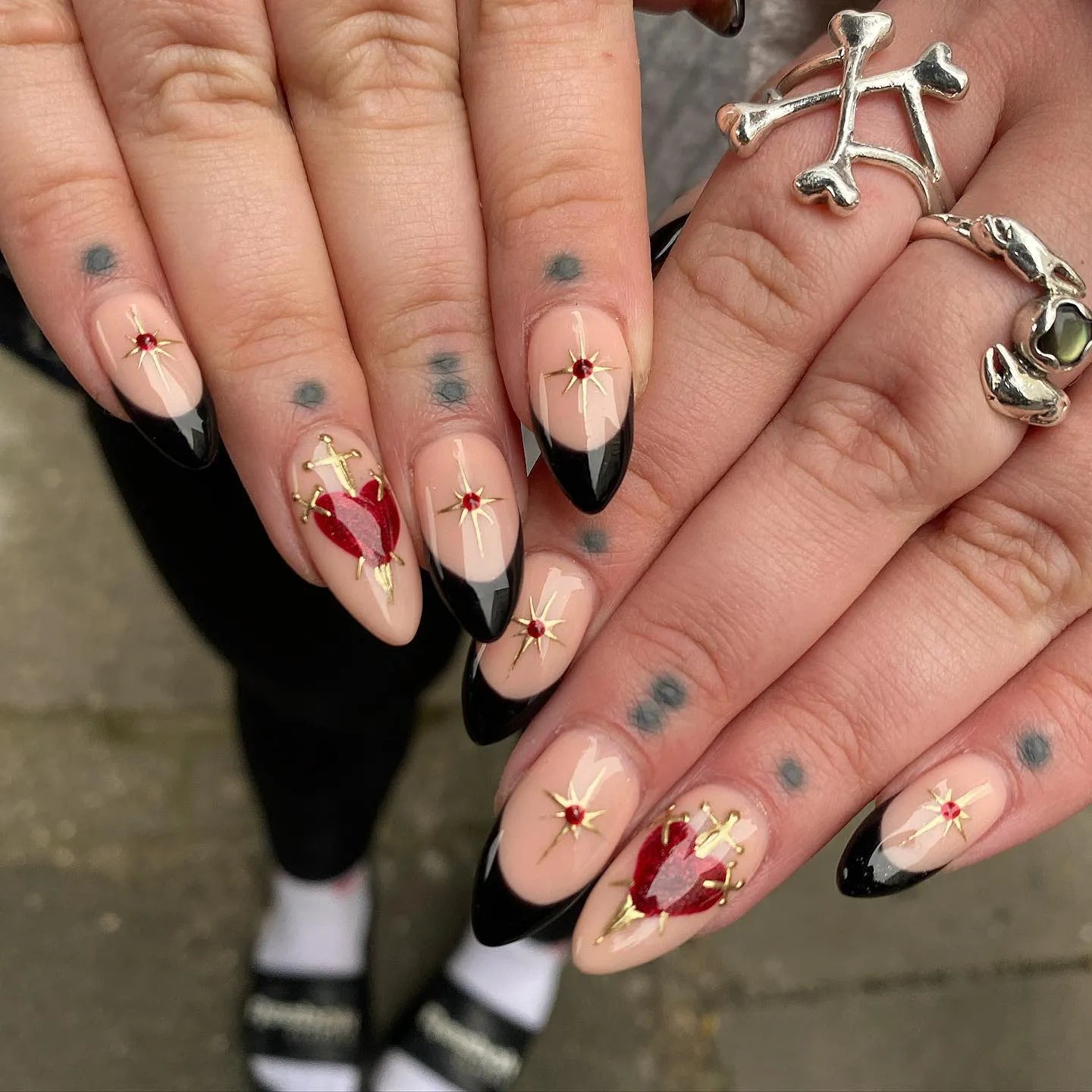 Handmade press-on nails with black French tips, gold stars, and red heart accents.