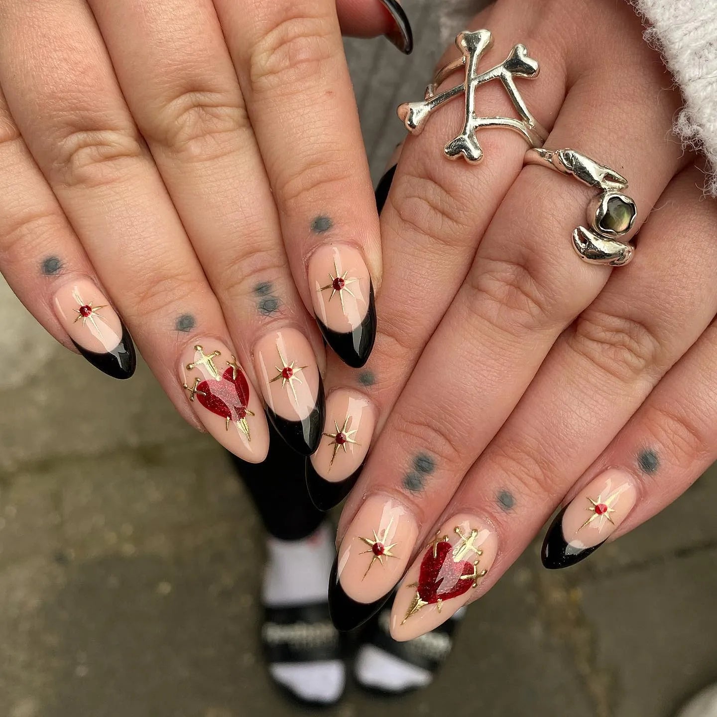 Hand with handmade gothic press-on nails featuring black French tips and Sacred Heart designs