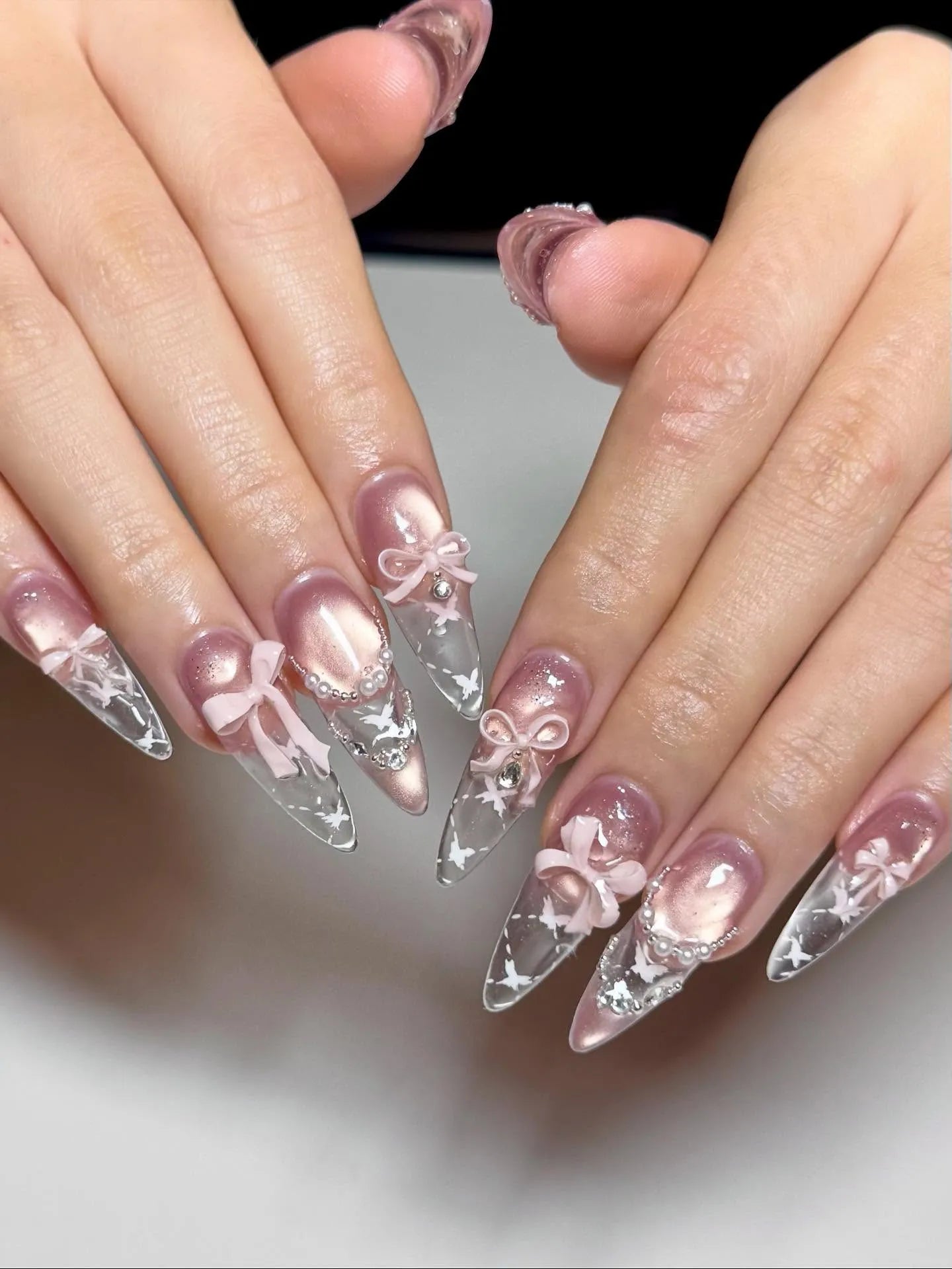 Handmade stiletto press-on nails with pink ribbon bows, pearls, and celestial star accents.