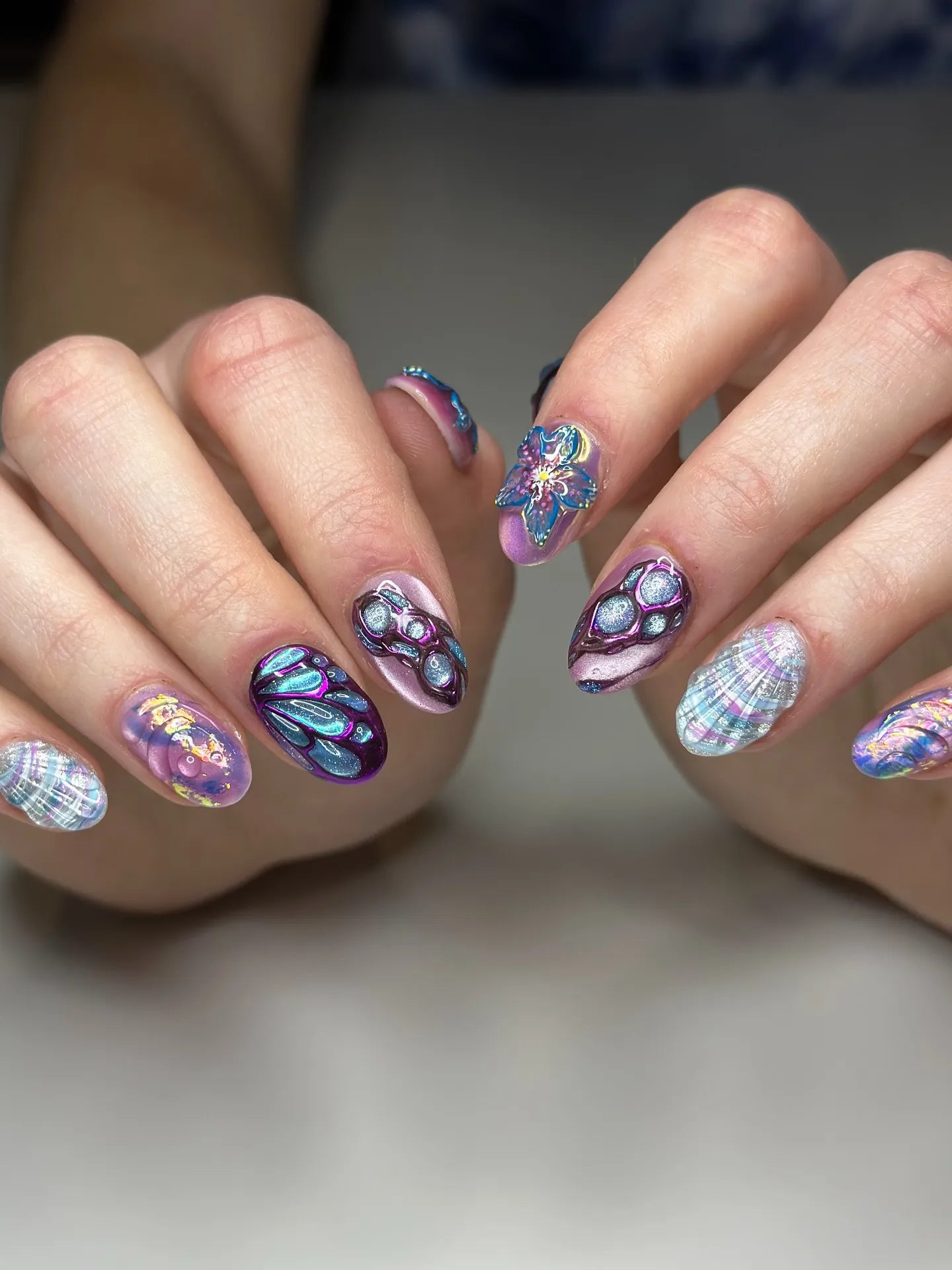 Handmade iridescent butterfly and shell fantasy press-on nails with 3D designs on hands